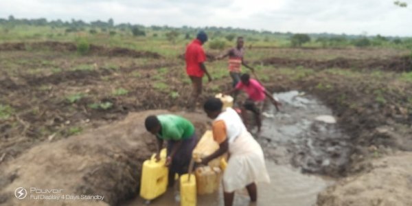 Irene my wife and the children fetching water for irrigation of our melon. We have had no rain yet its flowering.