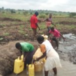 Irene my wife and the children fetching water for irrigation of our melon. We have had no rain yet its flowering.