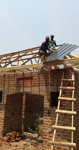 Nailing of the first iron sheet at the house 